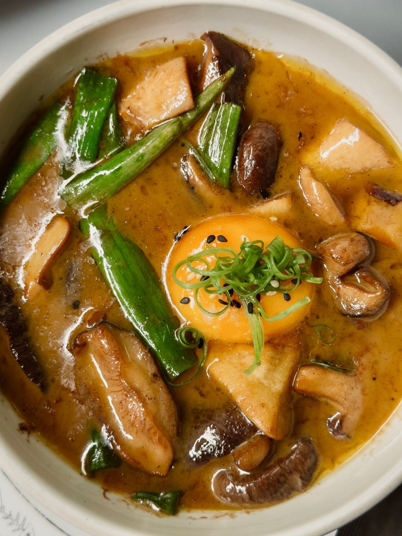 Curry de perto, com gema, cogumelos, vagens e cebolinha.
