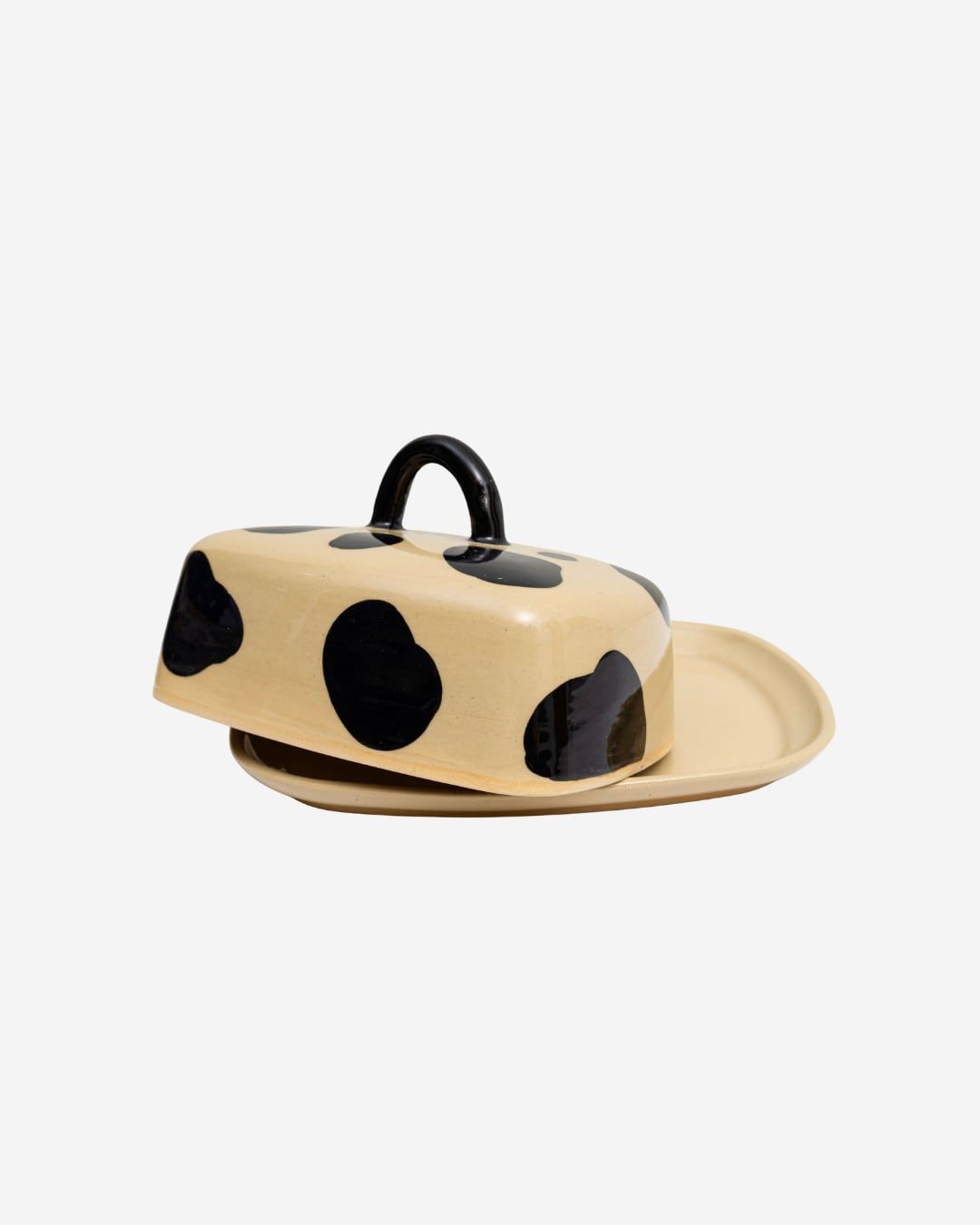 Peça de cerâmica com tampa, creme com manchas pretas como uma vaquinha.